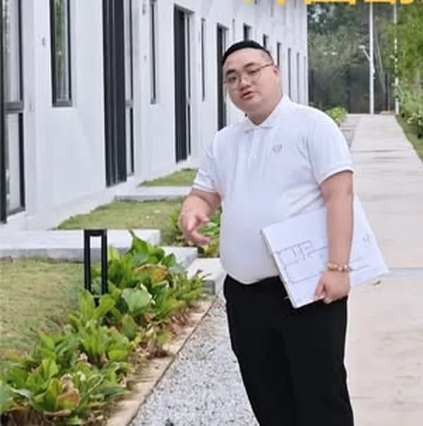 师傅手持图纸走过排屋外围